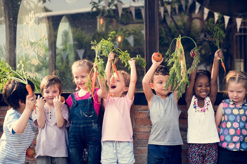 Group of children smiling and holding vegetable