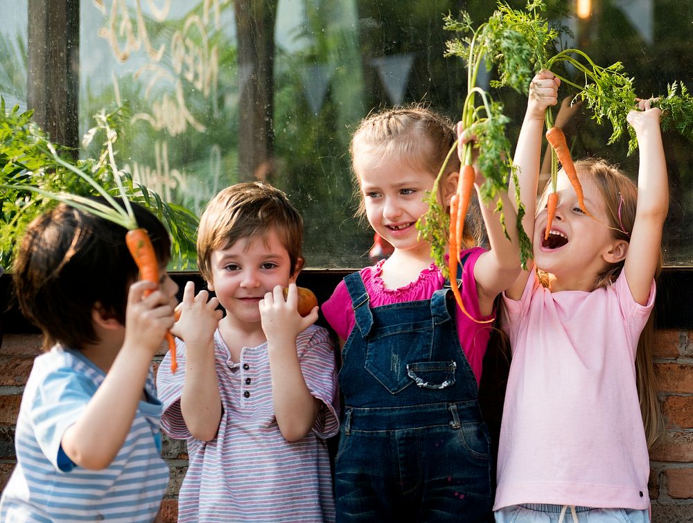 Group of children smiling and holding vegetable