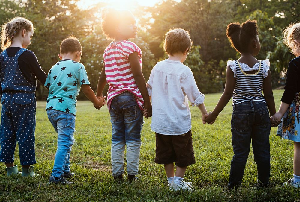 Group of kindergarten kids friends holding hands playing at park