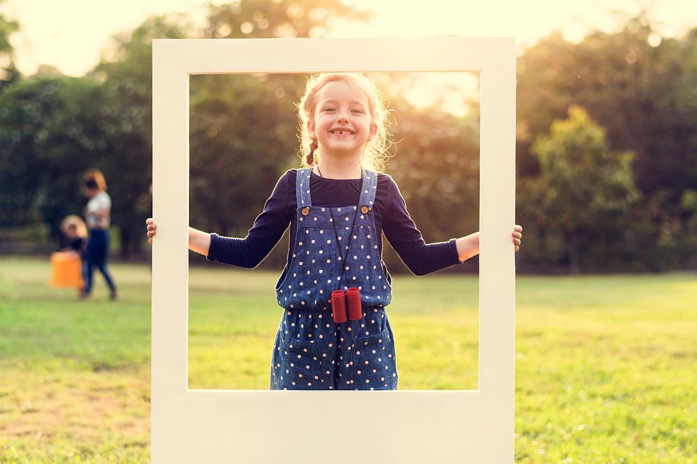 A girl is holding a frame in a park