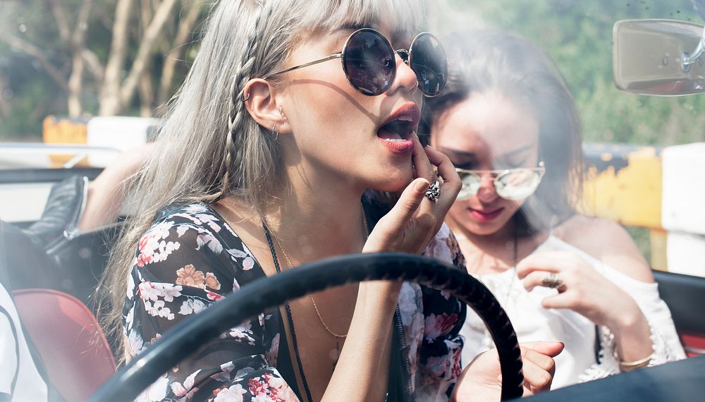 Woman Sitting in a Car Putting Lipstick on Lips with Rear Mirror