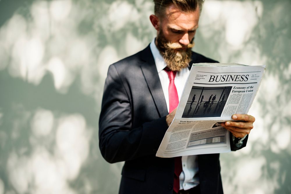 Businessman standing and reading newspaper
