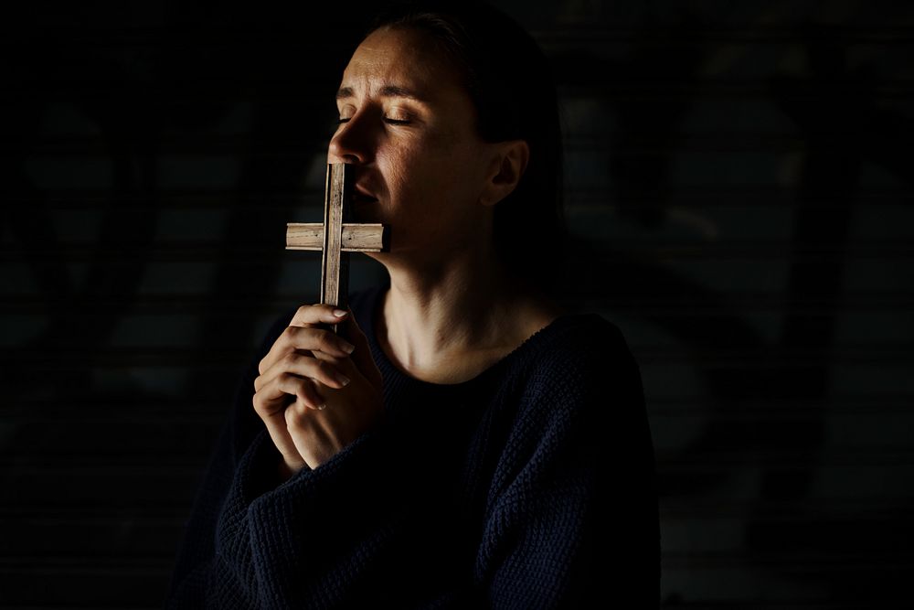 Woman holding cross praying for god religion