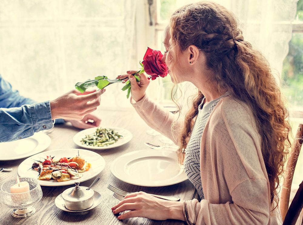 Woman on a date smelling a red rose