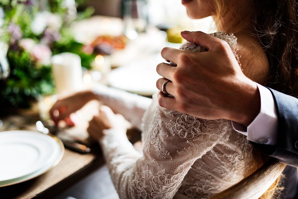 Groom's hand holding his bride close