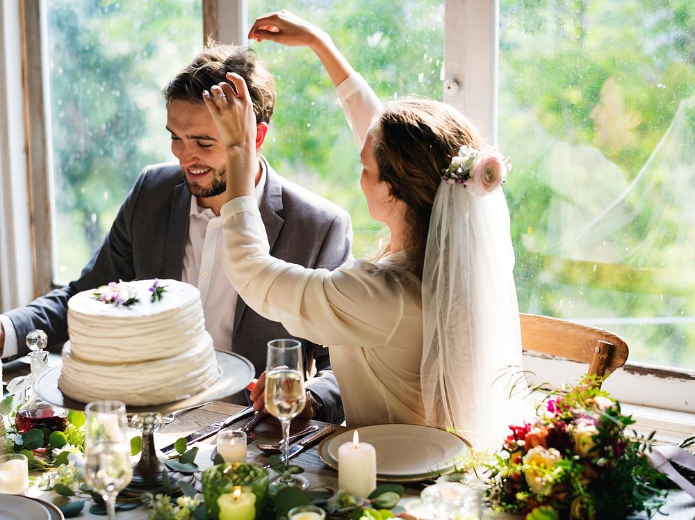 Bride playing with groom's hair at reception table