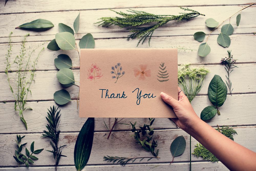 Hand Holding Show Thank You Card with Green Leaves Background
