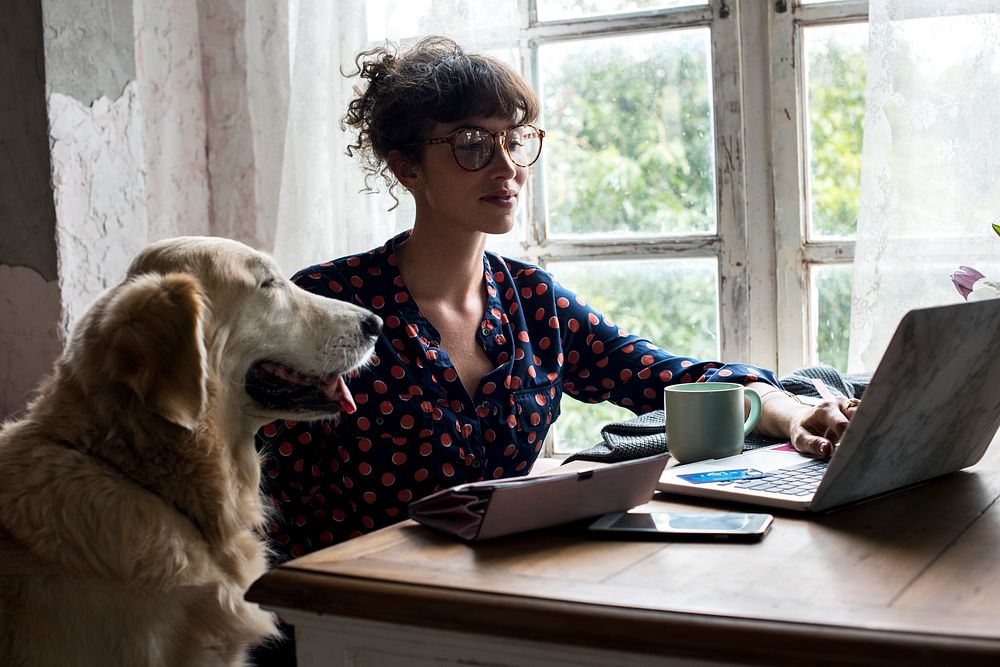 Woman using laptop on leisure day with golden retriever