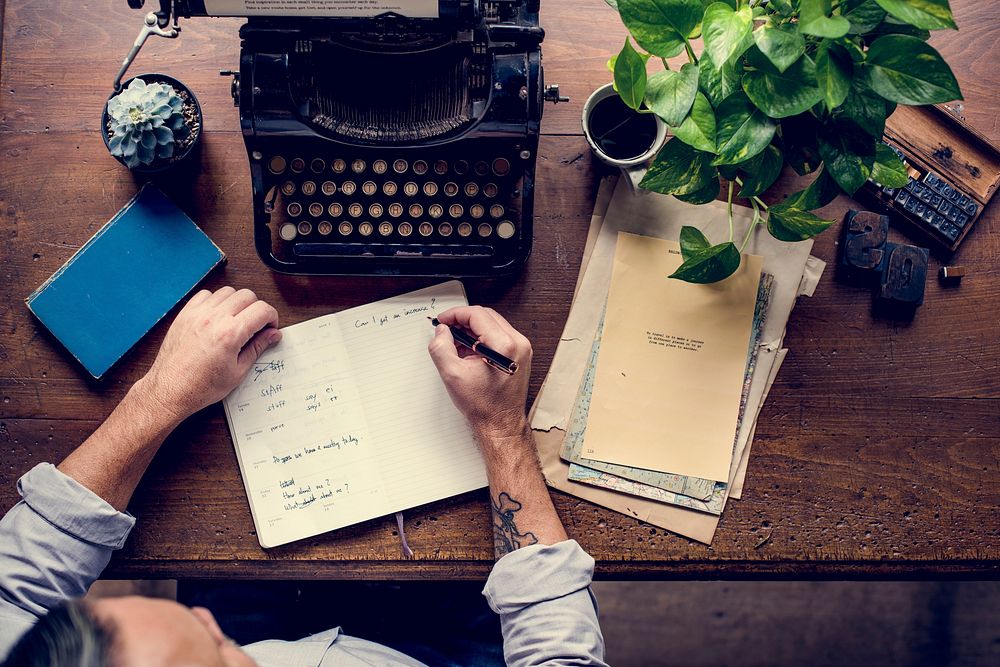 Man writing on notebook and vintage typewriter