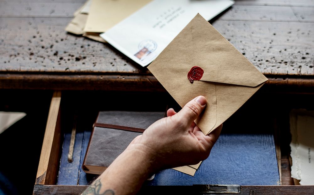 Human hand holding wax seal envelope correspondence
