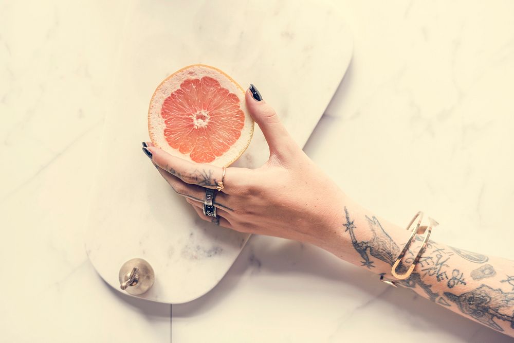 Tattoo Woman Hand Getting Orange with Marble Background