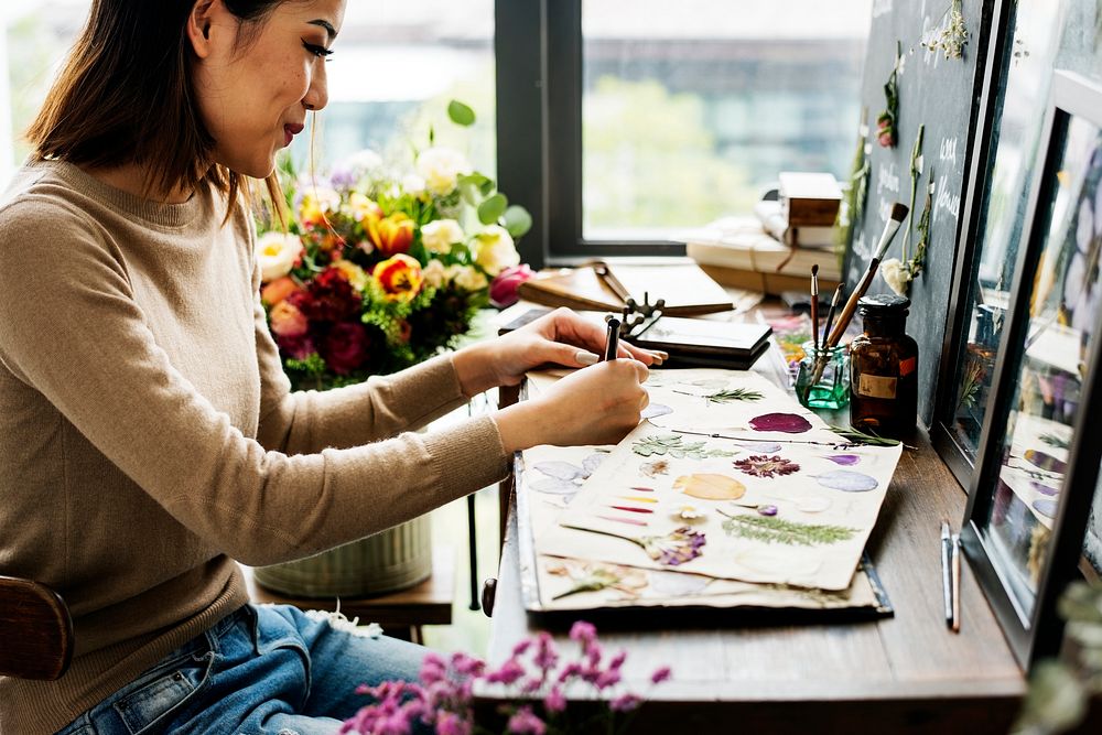 Woman writing as she creates floral project 
