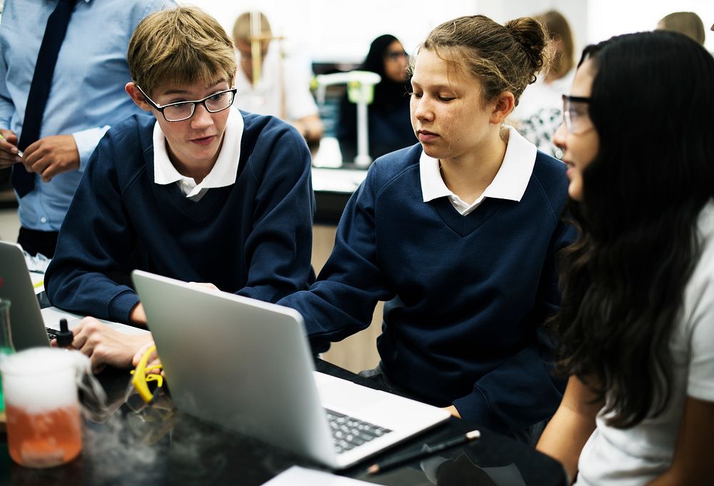 Group of diverse hight school students using laptop in science laboratory class