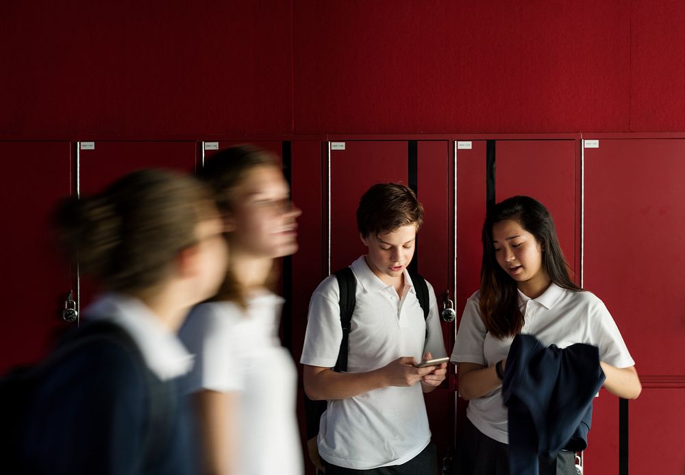 Group of students using mobile phone on hallway