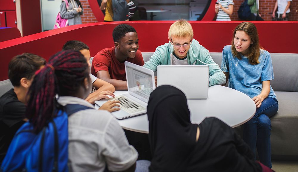 Group of diverse high school students using laptop