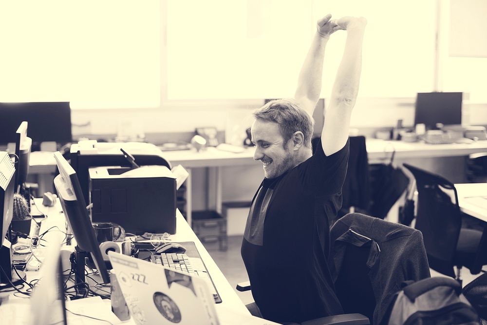 Man stretching arms during break time at office