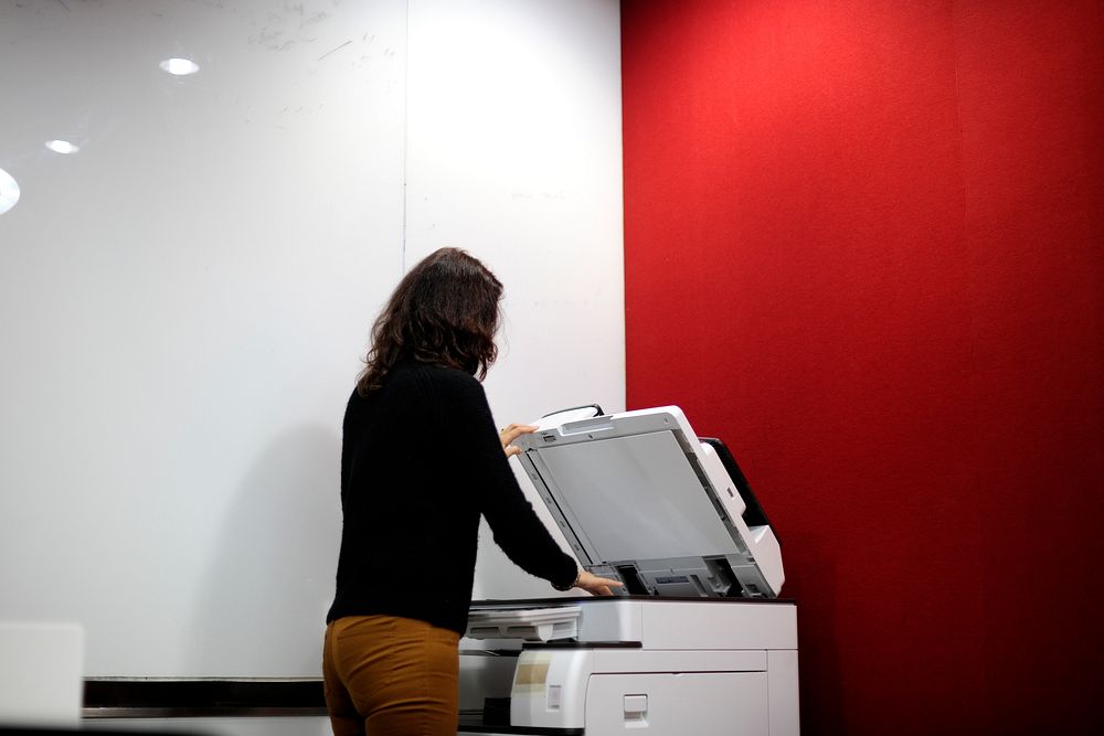 Woman using machine to copy document