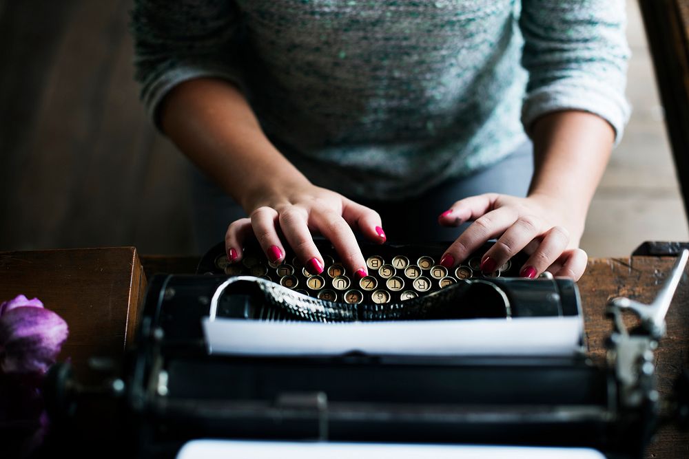Woman typing vintage typewriter on wooden table
