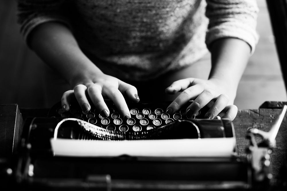 Woman typing vintage typewriter on wooden table