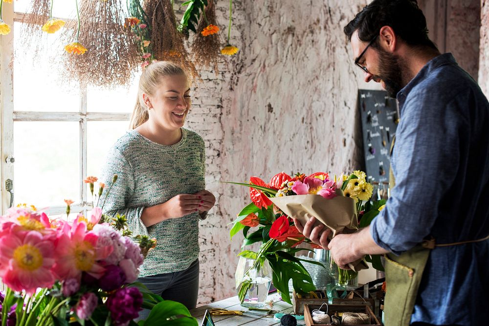 Flower shop owner selling bouquet to a customer