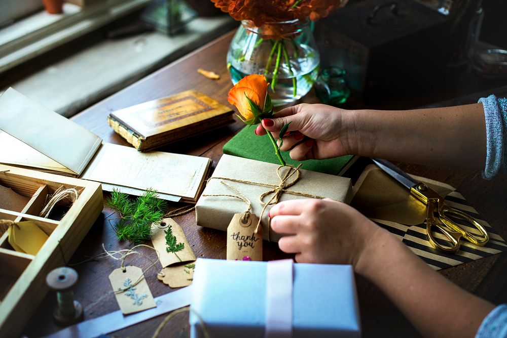 Hands diy wrapping gift box on wooden table