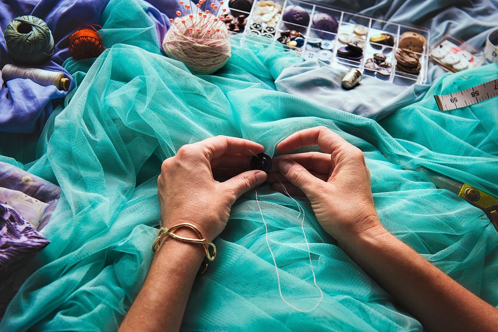Closeup of hands sewing button handicraft handmade