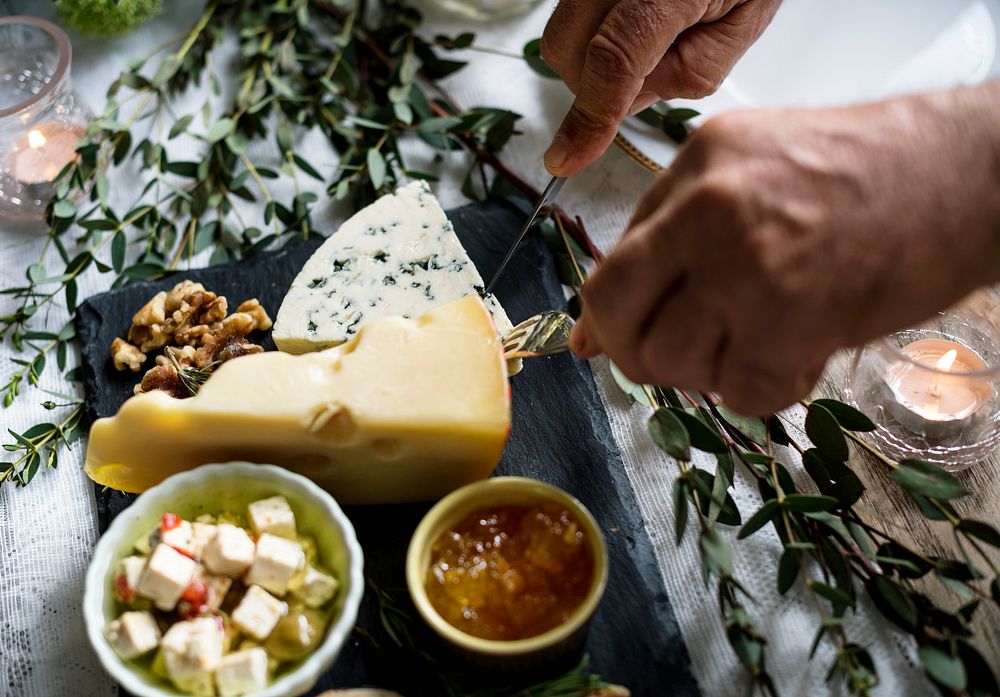 Close up of hands getting cheese on a plate