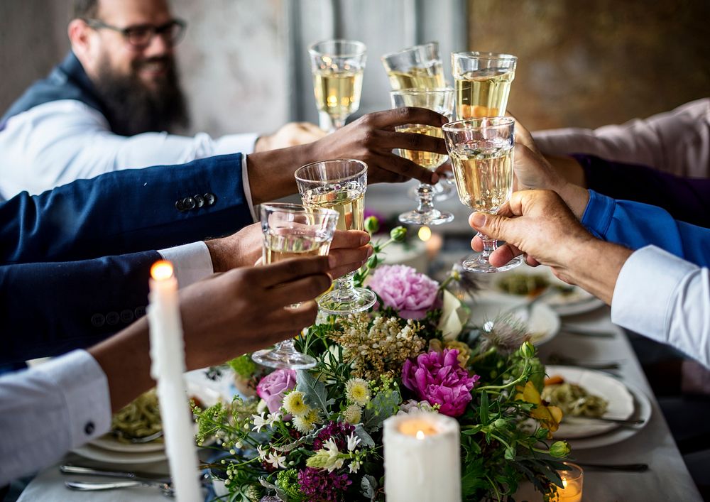 People holding their champagne glasses for a toast at a wedding table