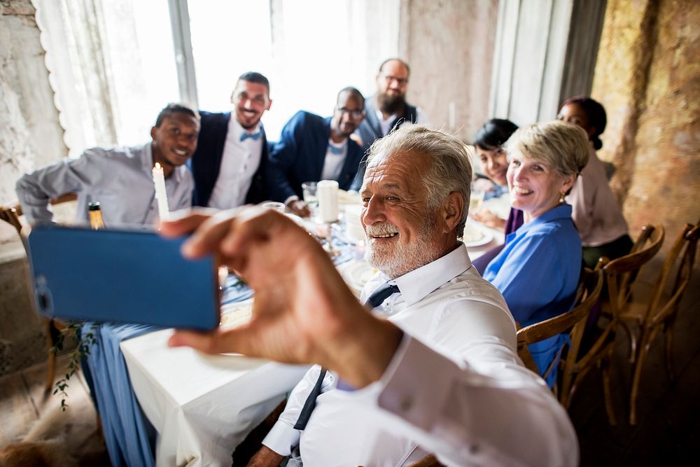 Group of diverse friends taking selfie together at wedding reception