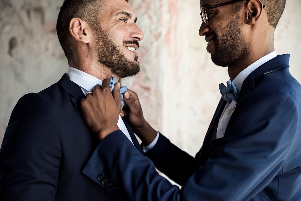 Closeup of gay couple helping each other dress up