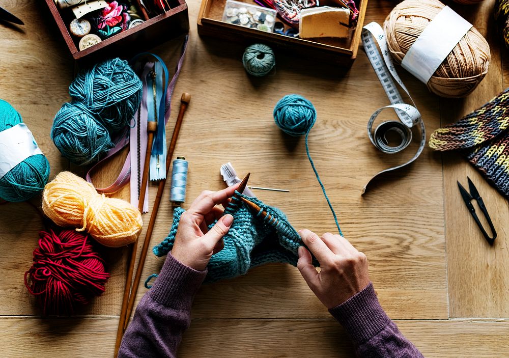 Aerial view of hands knitting on wooden table