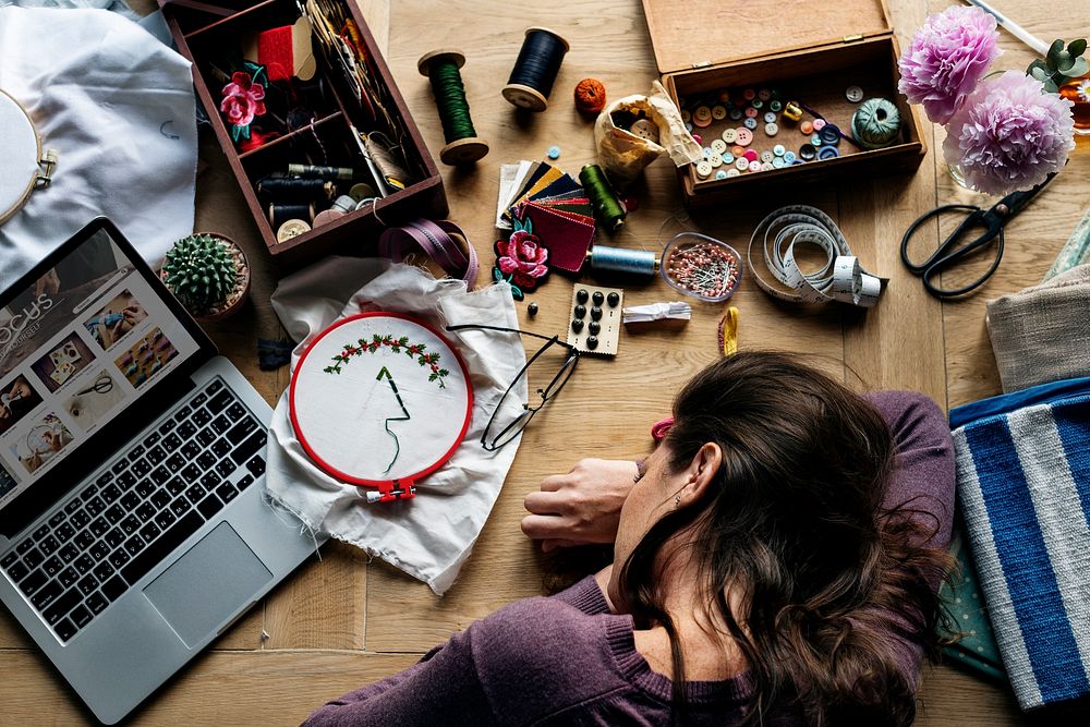 Aerial view of woman taking a nap on wooden table with handicraft work