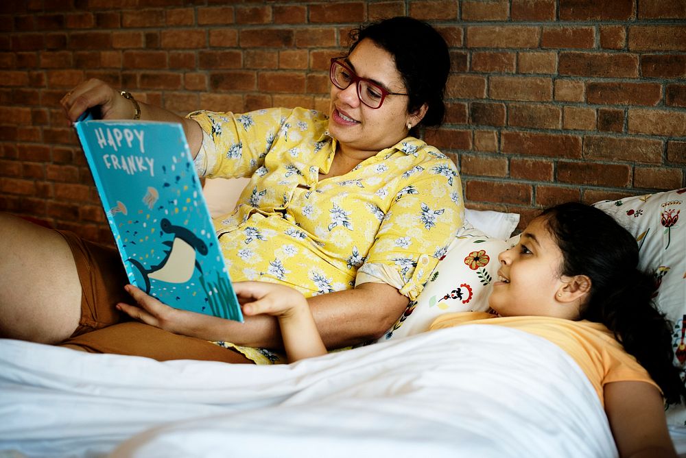 Mother reading bed time story to her daughter