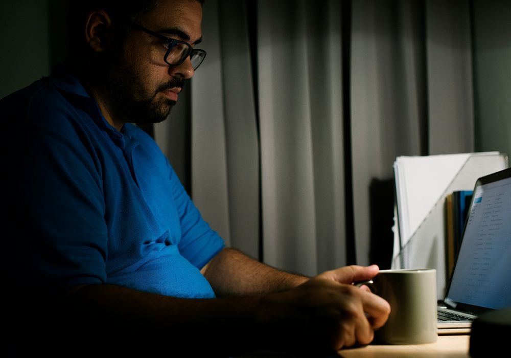 Man working with laptop on the table in the dark