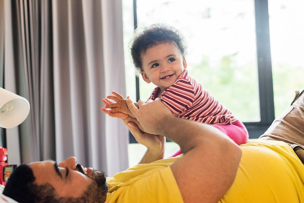 Dad playing with little daughter in bedroom