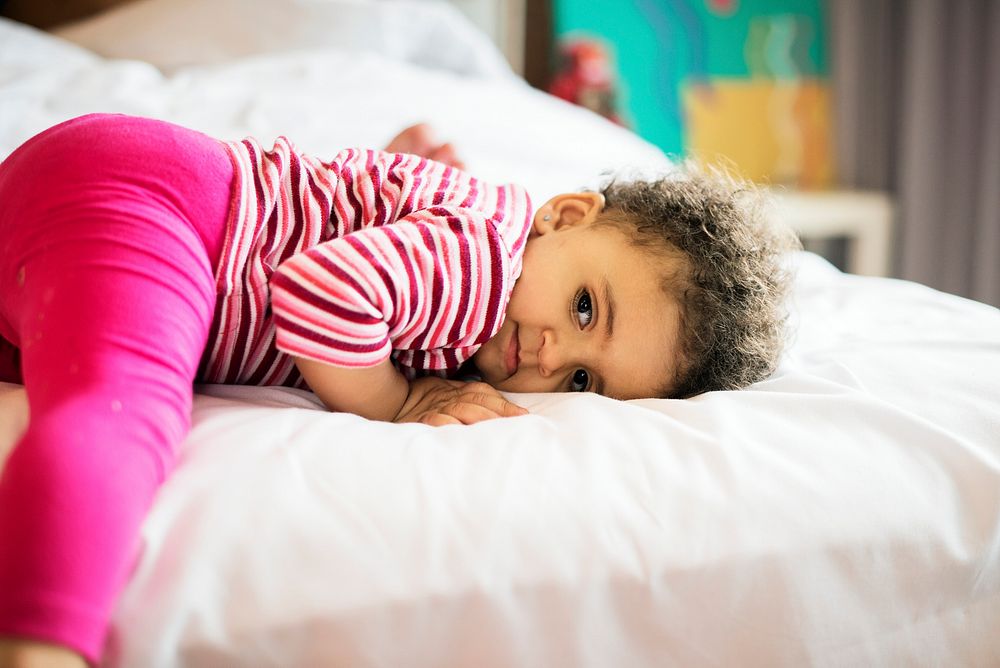 Little toddler girl lying down a on the foot of the bed
