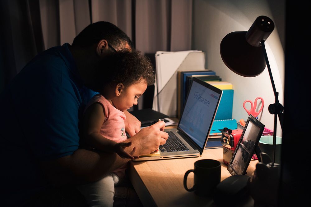 Dad with little girl working on laptop in a home office