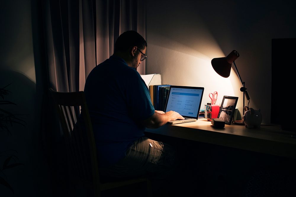 Man working in a dark home office with a laptop