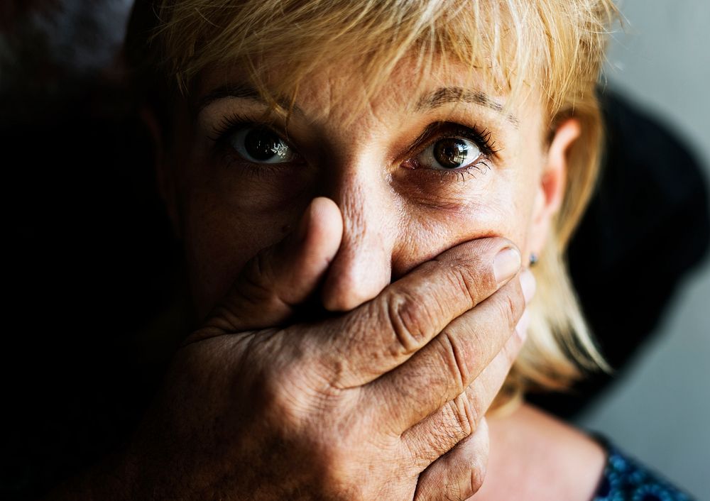 Closeup of caucasian woman with a hand covering her mouth 