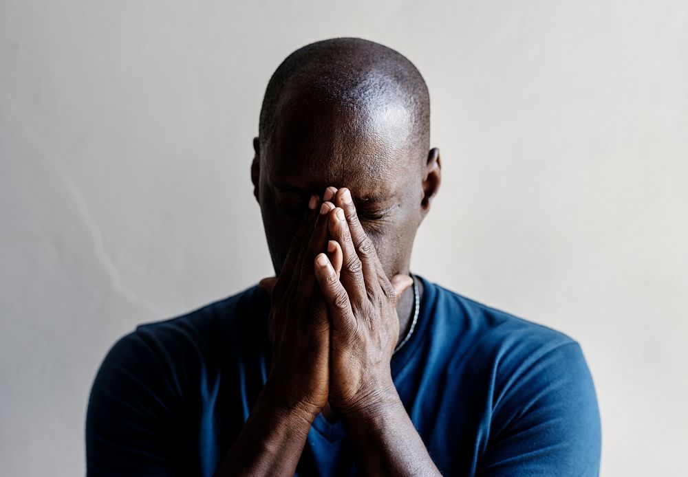 Black man with hands covered his face feeling worried