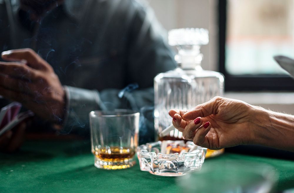 Close up of alcohol and hands holding a cigarette