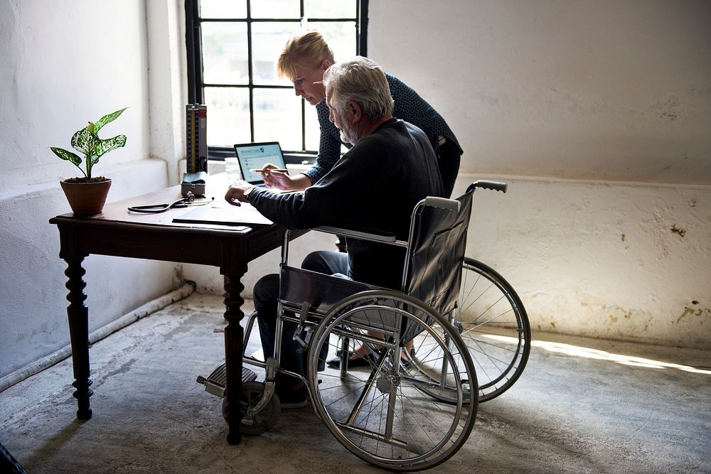 Side view of elderly man sitting on wheelchair looking at documentation 