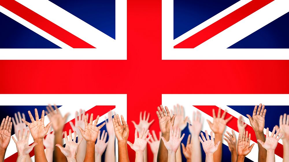 Group Of Multi-Ethnic Arms Outstretched With British Flag As A Background.
