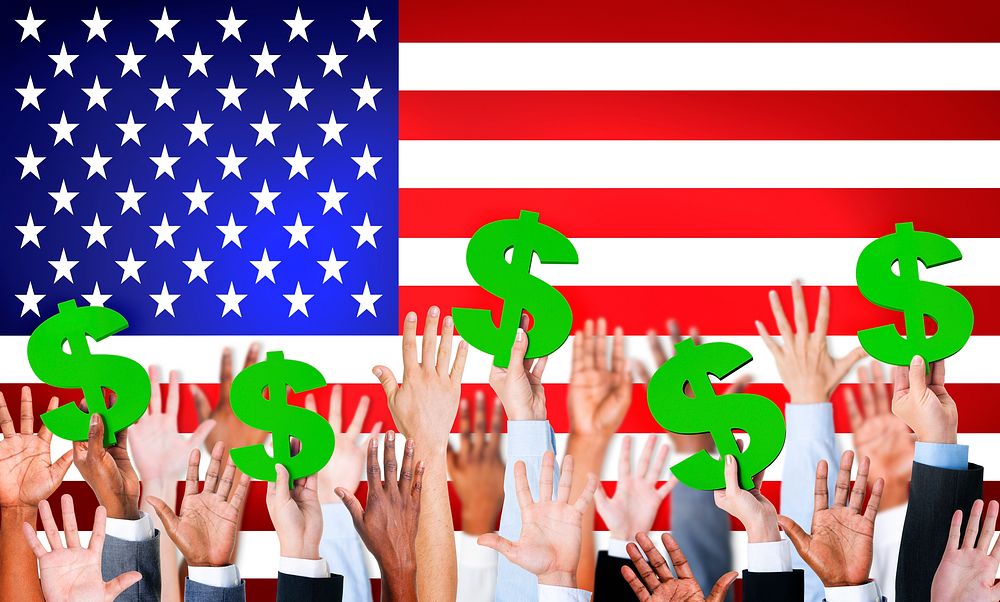 Multi-Ethnic Hands Holding Dollar Signs With Flag Of USA For The Background.