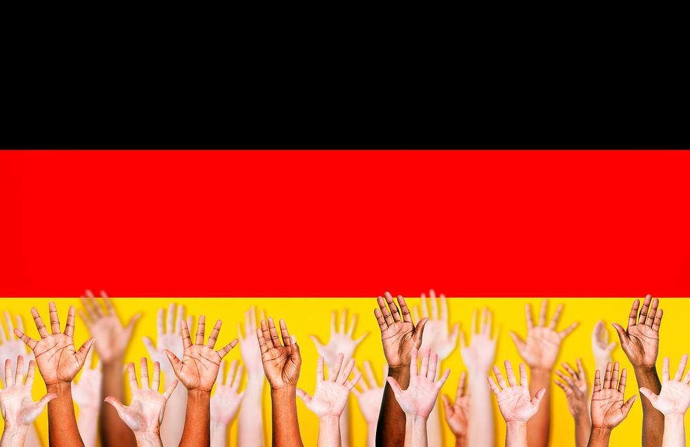 Group of Multi-Ethnic Arms Raised and a Flag of Germany as a Background
