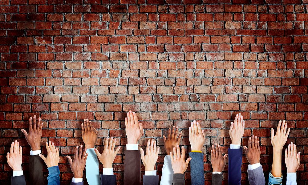 Group of Diverse Business Hands Raised on Brick Wall