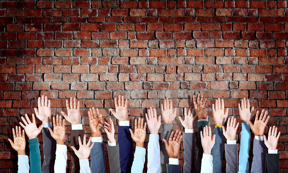 Group of Diverse Business Hands Raised on Brick Wall