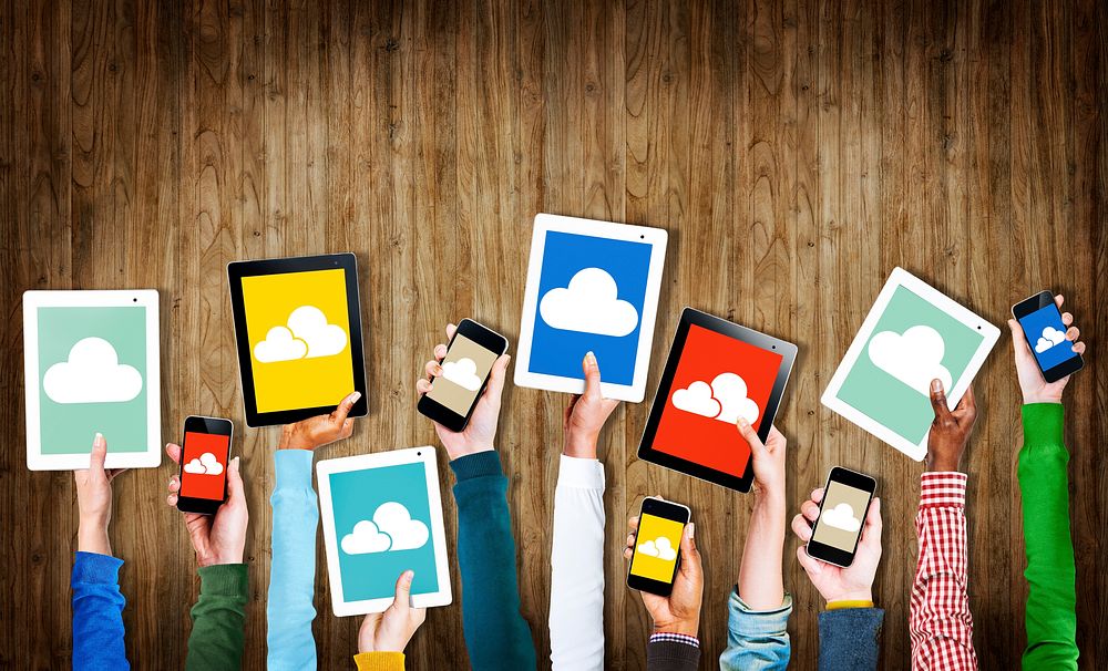 Group of Hands Holding Digital Devices with Cloud Symbols