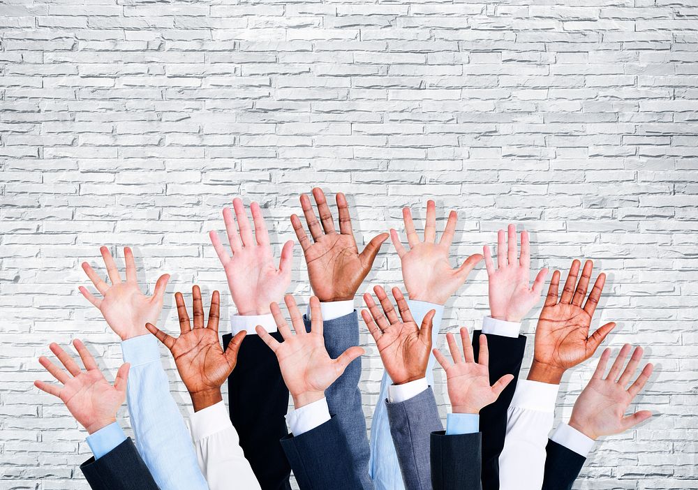 Group of business human arms raised with brick wall.