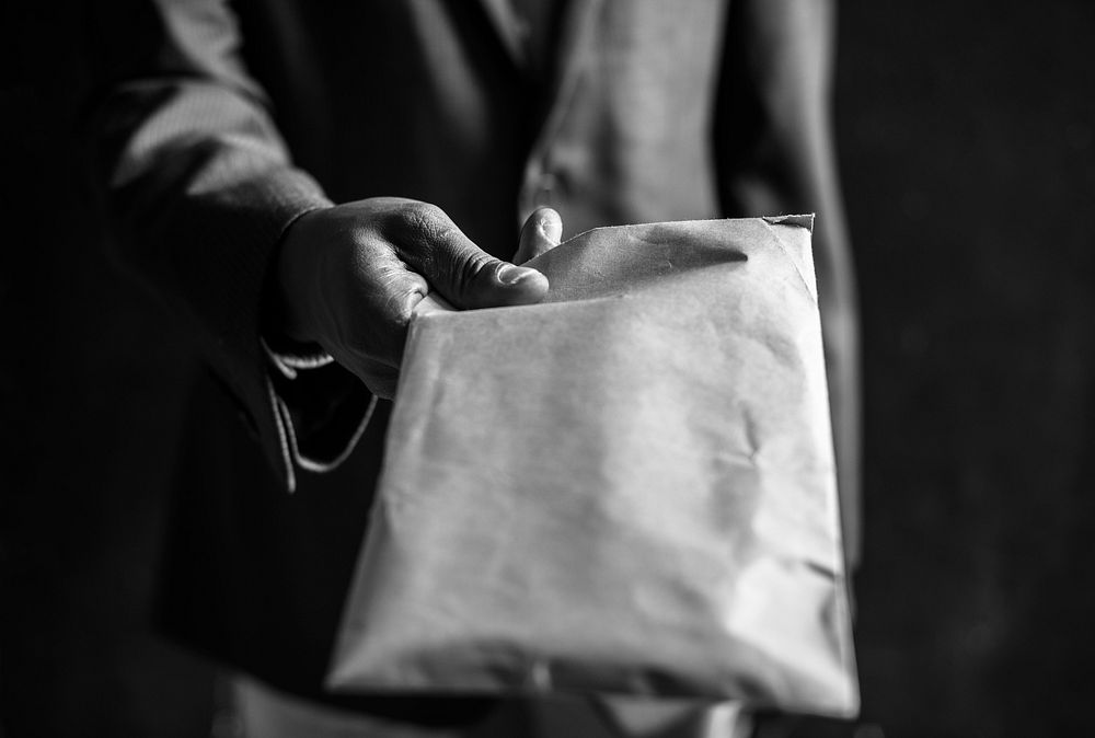 Hand handing over an envelope